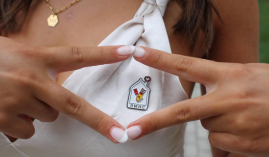 Alpha Delta Pi member wearing a white shirt with an RMHC button, holding her fingers in a diamond shape over the button